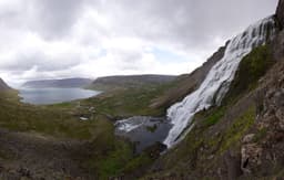 Dynjandi waterfall spreading down a tiered cliff face in the Westfjords, with lower cascades and a rocky river in front of it