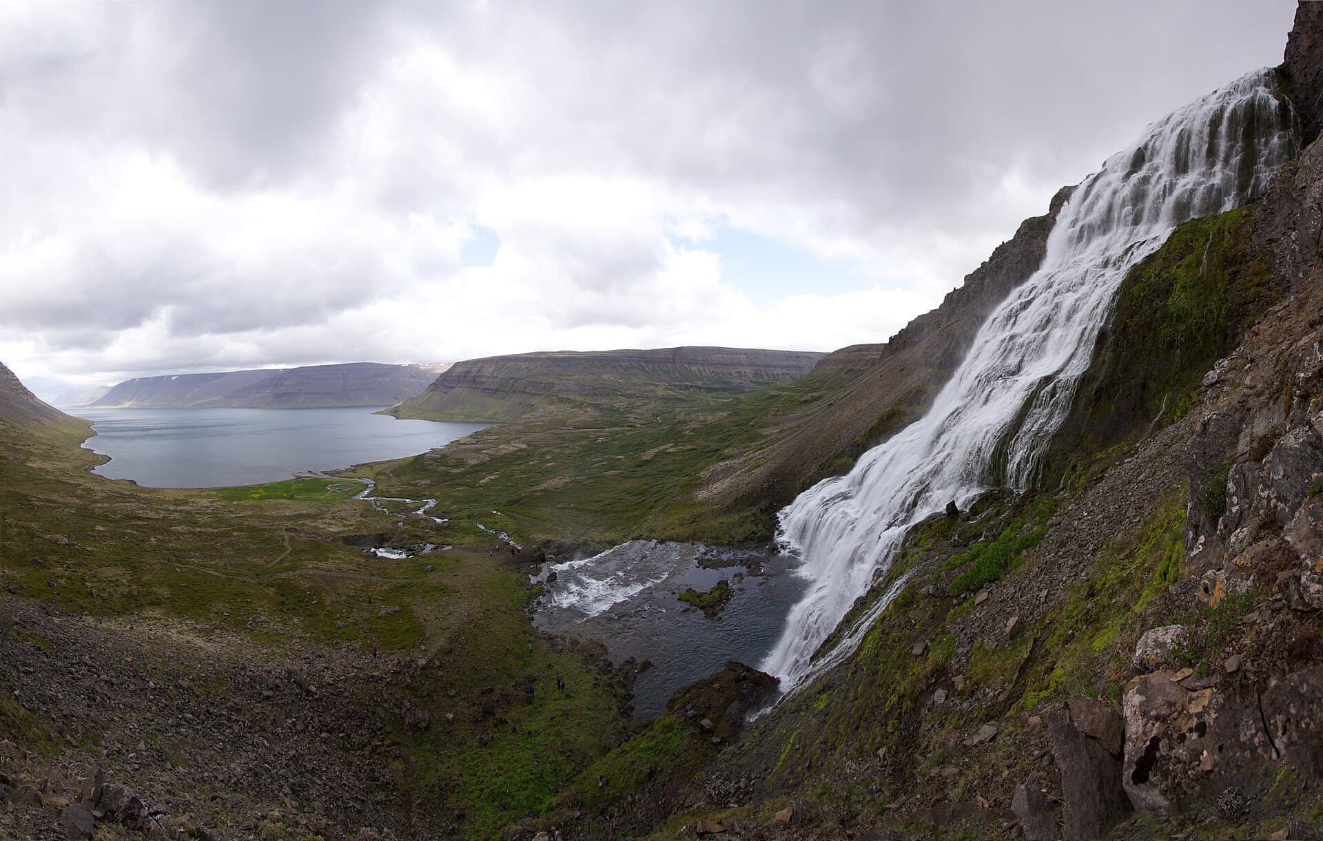 Dynjandi waterfall spreading down a tiered cliff face in the Westfjords, with lower cascades and a rocky river in front of it