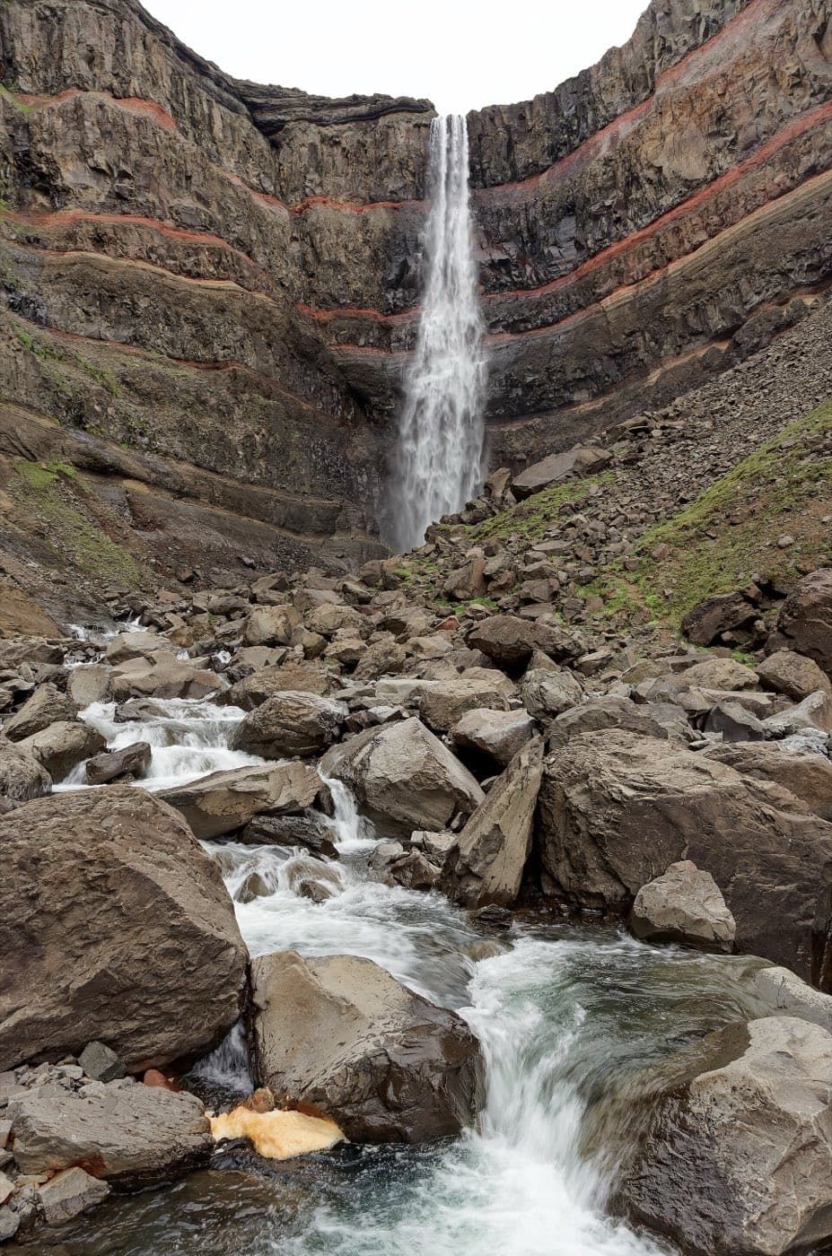 Hengifoss waterfall falling past red clay bands in east Iceland