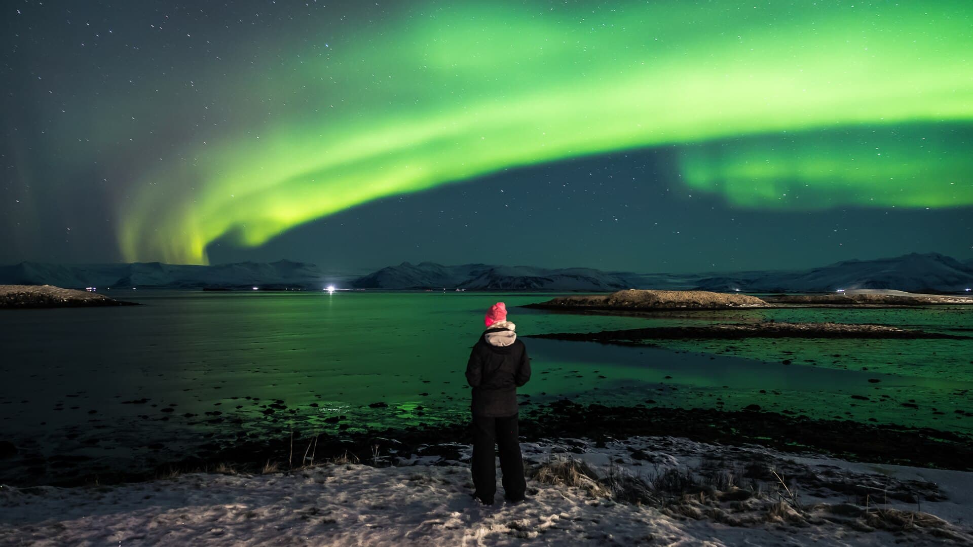 A green aurora arc across a star-filled Icelandic sky