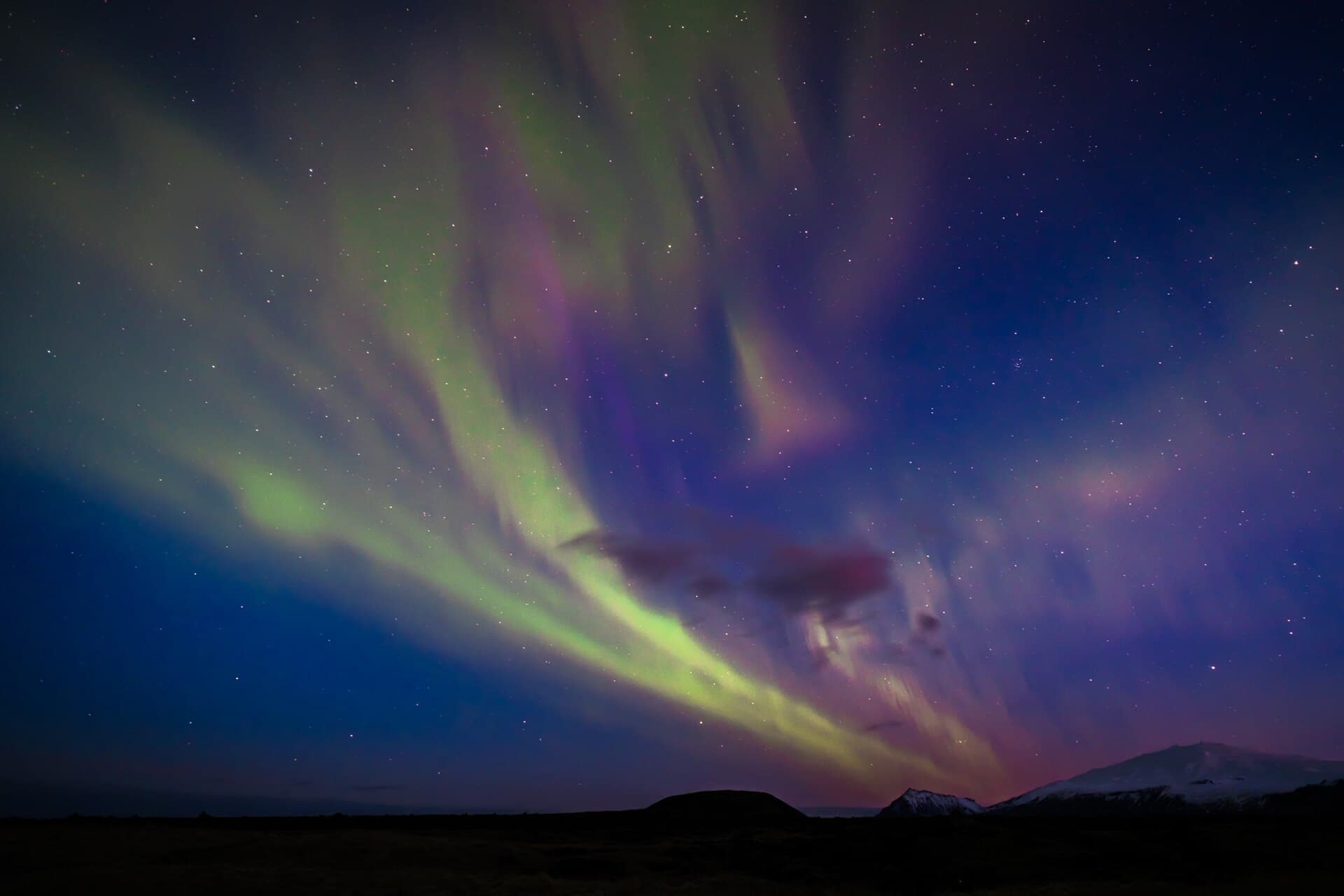 Northern lights curtains above a snowy landscape
